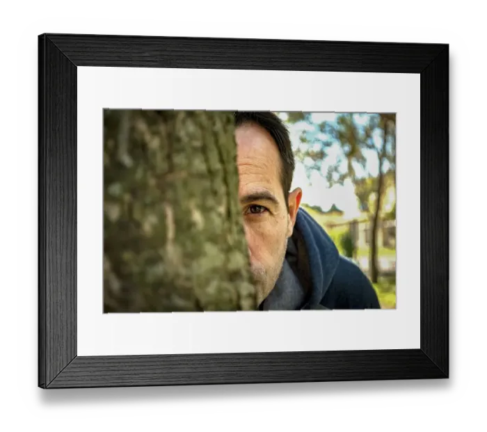 Framed Print : A man spying behind a tree Framed Print : A man spying behind a tree