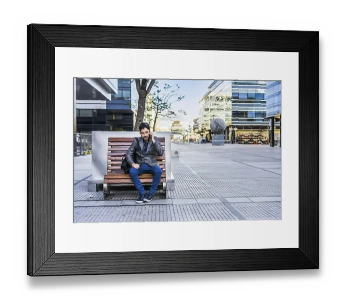 Framed Print : A businessman is talking on the cell phone while sitting on a bench in the street