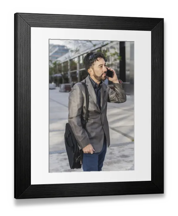 Framed Print : Portrait of a businessman talking on the cell phone outside his office