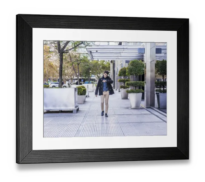 Framed Print : Businessman looking at his watch while walking near his office