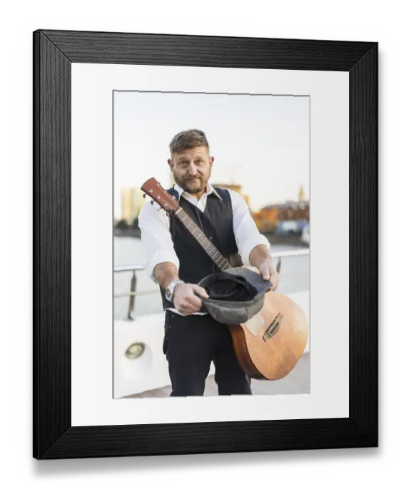 Framed Print : A street musician looking at camera and carrying his guitar while asking for tips