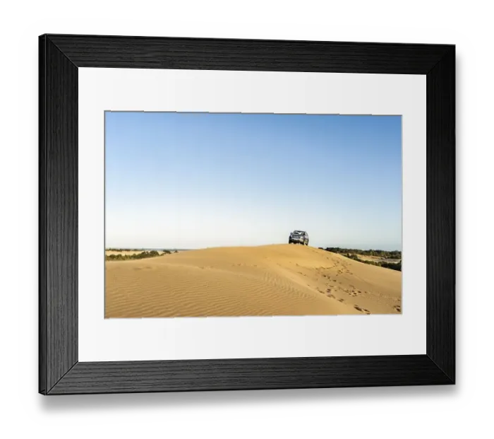 Framed Print : A man driving a 4x4 vehicle in a dune at sunset