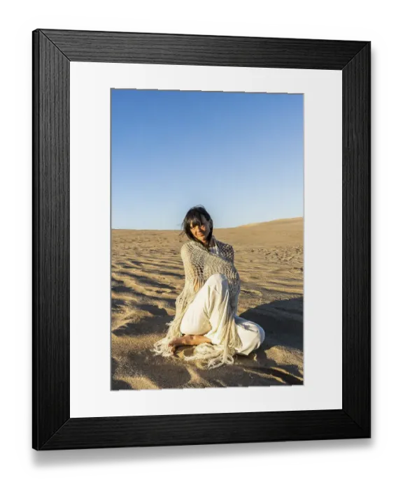 Framed Print : A woman dressed in white sitting on the sand at sunset