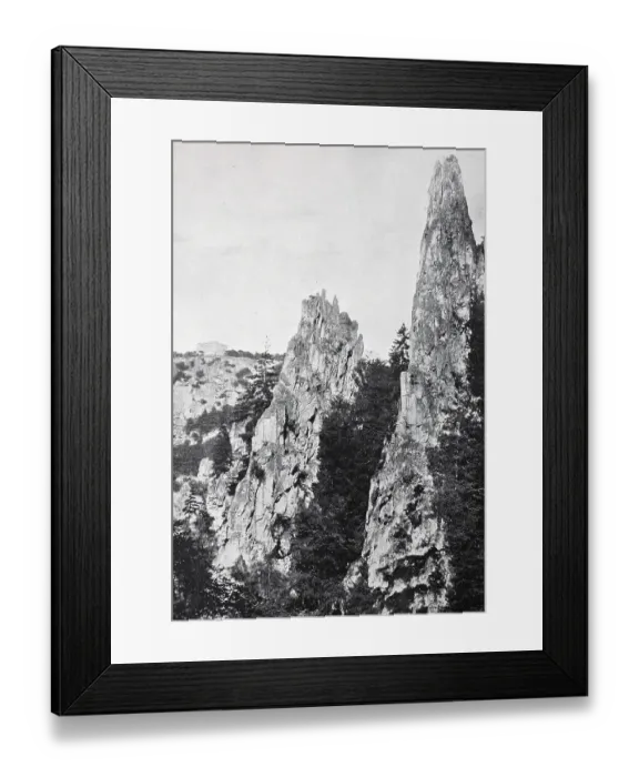 Framed Print : Steep and high rocks protrude from a wooded area