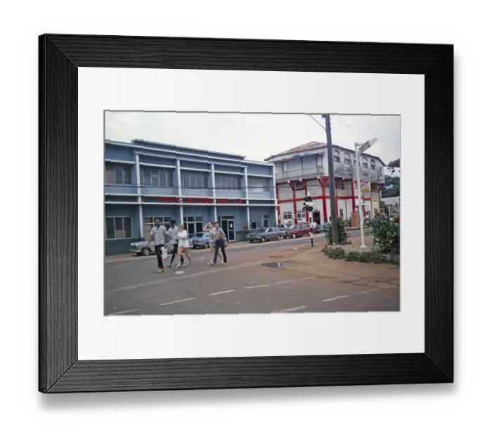 Framed Print : Street scene with people walking past the Follys Betting 1963 Ltd. building, Mandeville, Jamaica, 1970, Central America