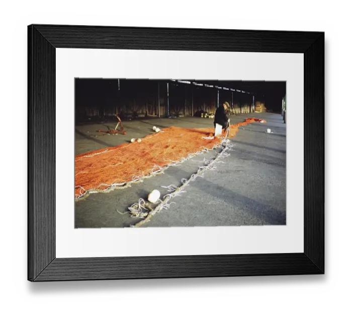 Framed Print : Man sitting in a storage shed mending a fishing net, unspecified location, Great Britain 1975