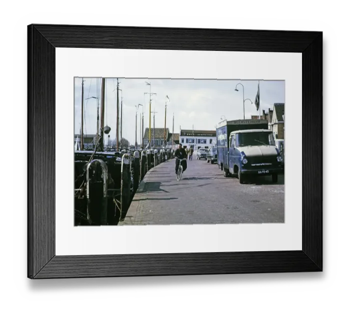 Framed Print : Volendam, Netherlands, 1973 Man riding his bicycle on the quay next to fishing boats Framed Print : Volendam, Netherlands, 1973 Man riding his bicycle on the quay next to fishing boats