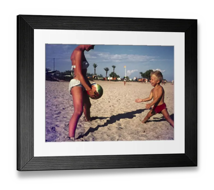 Framed Print : Mother and young son playing catch with a ball on sandy beach in Spain, 1966