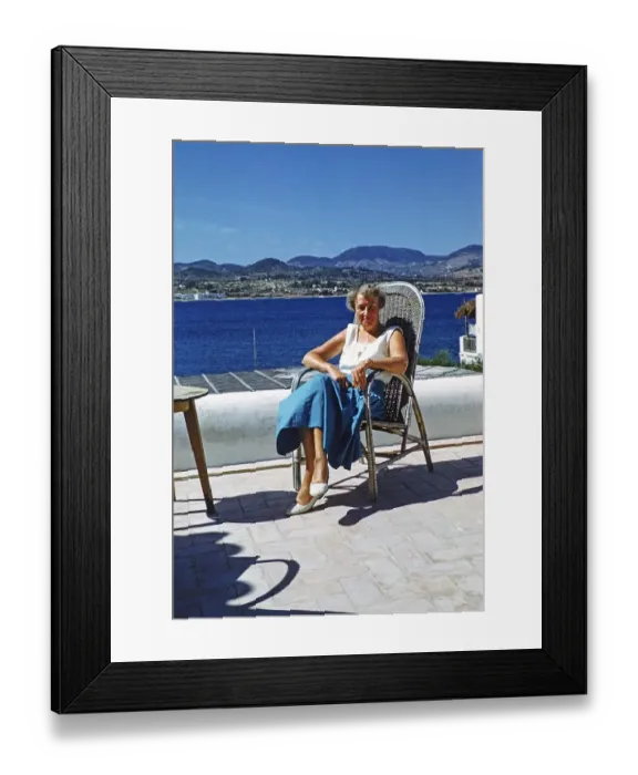 Framed Print : Touristin mittleren Alters sitzt in der Sonne auf einer Terrasse am Meer, Insel Ibiza, Balearen, Spanien, 1950er Jahre Framed Print : Touristin mittleren Alters sitzt in der Sonne auf einer Terrasse am Meer, Insel Ibiza, Balearen, Spanien, 1950er Jahre