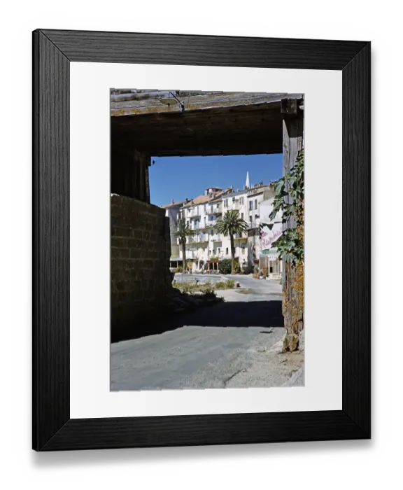 Framed Print : Historische Gebaeude am Wasser, eingerahmt von einem Torbogen in der Stadt Calvi, Korsika, Frankreich, Ende der 1950er Jahre