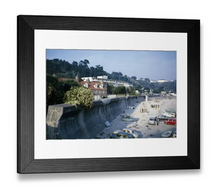 Framed Print : Autos und Menschen am Sandstrand vor einer grossen, gebogenen Kuestenschutzmauer, St Brelade, Jersey, Kanalinseln, 1964, Europe