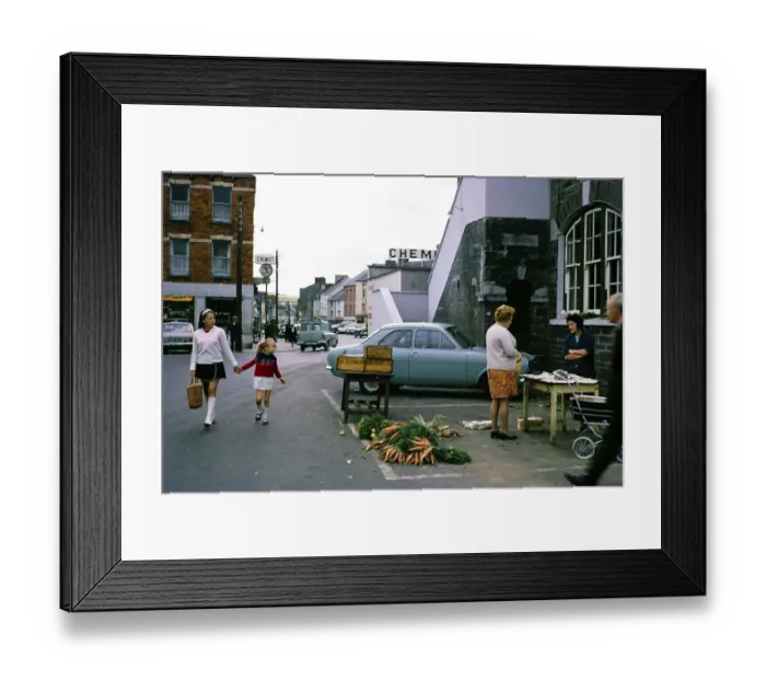 Framed Print : Small street market with carrots, people and traffic in Macroom, County Cork, Republic of Ireland, 1969 Framed Print : Small street market with carrots, people and traffic in Macroom, County Cork, Republic of Ireland, 1969