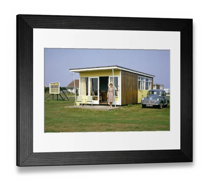 Framed Print : Woman standing in the doorway of a holiday home with parked Morris Minor, private holiday estate in Miami Beach, Sutton on Sea, Lincolnshire, England, Great Britain, 1960s