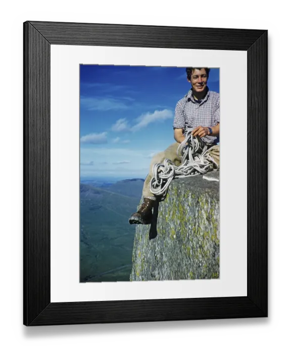 Framed Print : Young male climber sitting high up on a rock and holding a climbing rope, probably North Wales, Great Britain, around 1958