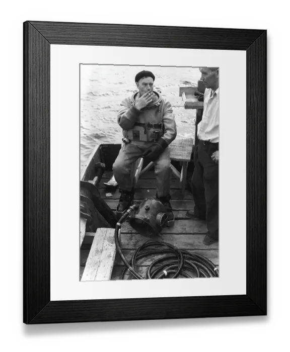 Framed Print : A diver in 1953, sitting in his diving suit and smoking a cigarette after a dive. One would have thought he would be happy only breathing the fresh air, once above the surface