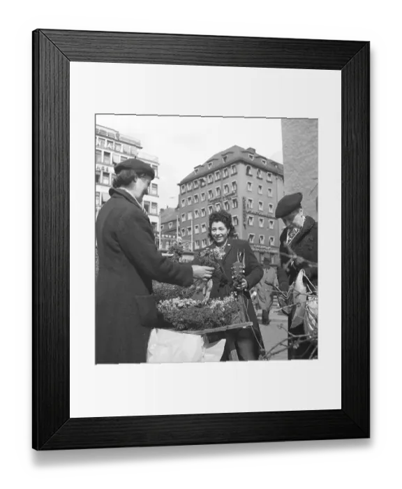 Framed Print : 1945 at Hoetorget in Stockholm Sweden. A lively scene at the outdoor flower market. Three women, dressed in mid-1940s coats and berets, engage in a cheerful exchange over a stall brimming with blooming plants and flowers
