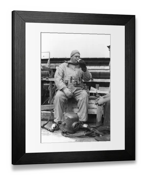 Framed Print : A diver in 1953, sitting in his diving suit and drinking coffee
