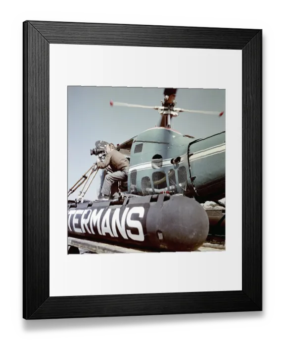Framed Print : Filming in the 1950s. A cinematographer is standing half way out of a helicopter when filming something. The film camera is mounted on a tripod. Ostermans was a swedish company specialized in helicopter transports Framed Print : Filming in the 1950s. A cinematographer is standing half way out of a helicopter when filming something. The film camera is mounted on a tripod. Ostermans was a swedish company specialized in helicopter transports