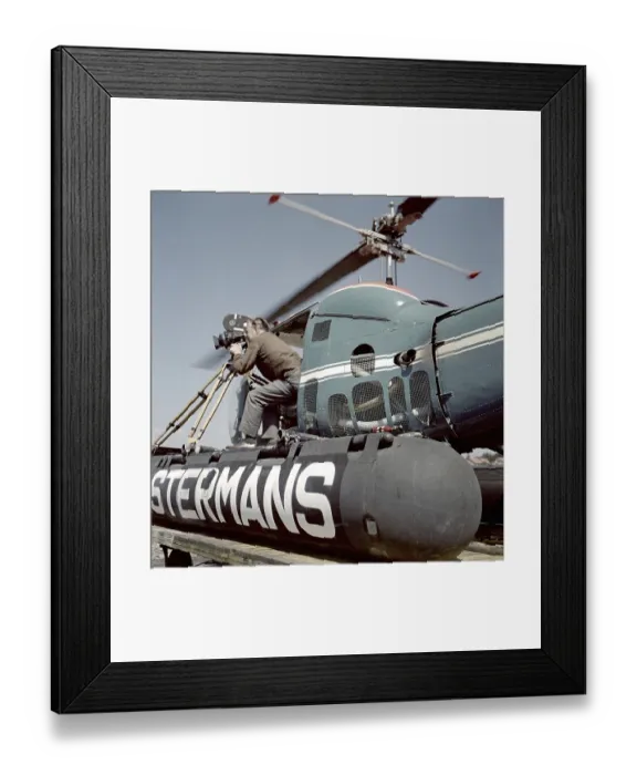 Framed Print : Filming in the 1950s. A cinematographer is standing half way out of a helicopter when filming something. The film camera is mounted on a tripod. Ostermans was a swedish company specialized in helicopter transports Framed Print : Filming in the 1950s. A cinematographer is standing half way out of a helicopter when filming something. The film camera is mounted on a tripod. Ostermans was a swedish company specialized in helicopter transports