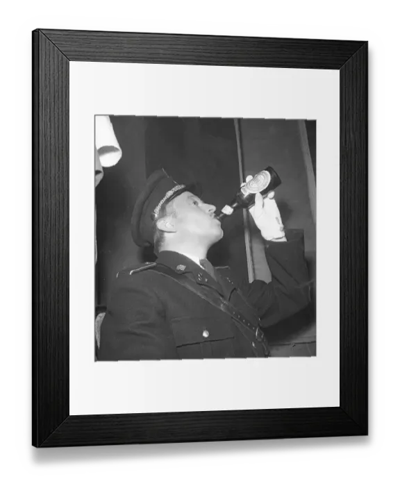 Framed Print : The 1940s. A man dressed in uniform drinks beer from a bottle made by the Danish brewery Tuborg