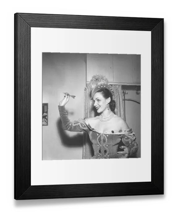Framed Print : Throwing darts 1951. Actress Ulla Sallert is seen aiming at the dart board to throw the dart. This is backstage at the theater. Kristoffersson Ref BE38-2