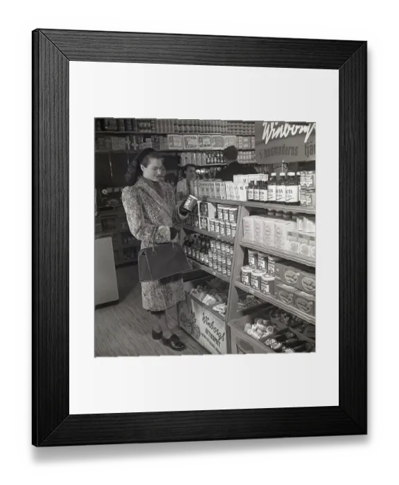 Framed Print : A woman shopping for food in the 1940s. A young woman is shopping in a self-service shop. She takes a closer look at one of Winborg's products, a fruit marmalade