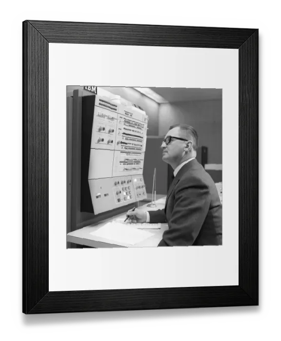 Framed Print : In the 1960s. Interior of a room with computers and people on the job of handling them and register and reading information. A sign above the mainframe computer says IBM 360