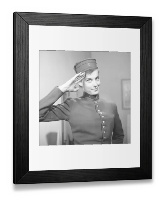 Framed Print : A young woman in a uniform saluting in 1956. On the cap and on the collar of the uniform is the number 7. The uniform-like clothes look like those worn by employees in cinemas, circuses, hotels or similar, where people work with service