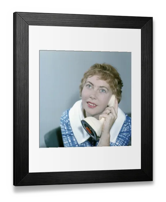 Framed Print : 1950s telephone. A young woman is talking on the telephone. A Swedish on-piece plastic telephone created by Ericsson Company of Sweden and launched 1956