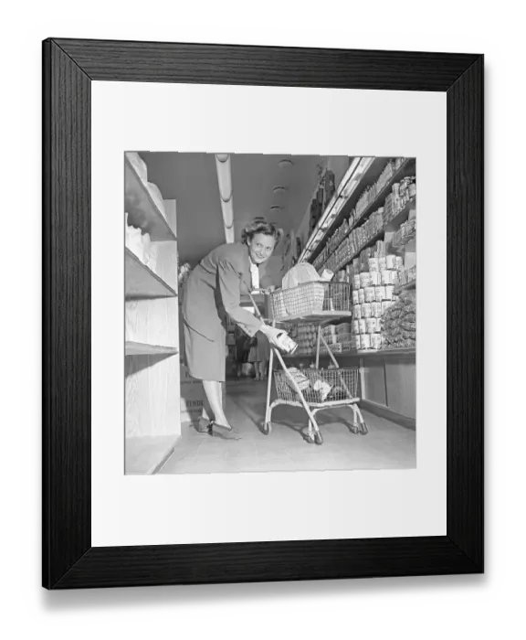 Framed Print : Shopping in the 1940s. A woman shops in a self service store