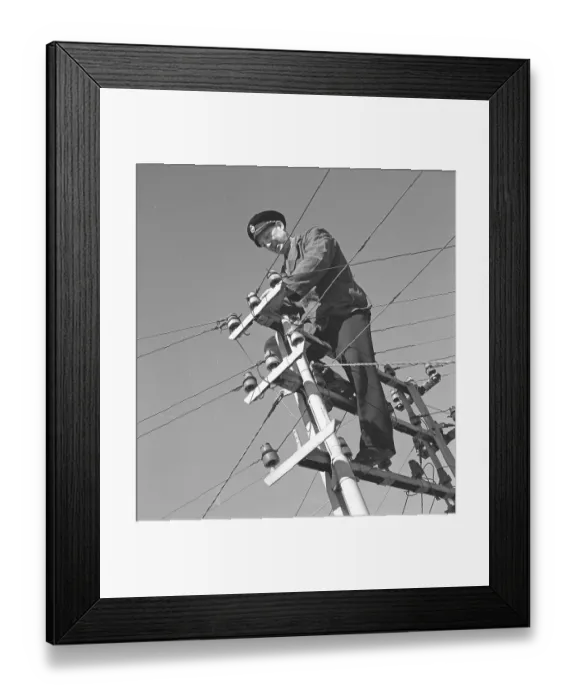 Framed Print : In the 1940s. A man is seen climbing on top of an electrical pole with power wires