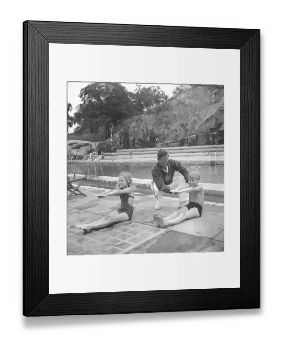 Framed Print : Swimming school in the 1940s. A boy and a girl practice stretching their arms together as you should do when swimming. A swimming instructor is there to give instructions. The place is the swimming school at Vanadisbadet in Stockholm June 1940 Framed Print : Swimming school in the 1940s. A boy and a girl practice stretching their arms together as you should do when swimming. A swimming instructor is there to give instructions. The place is the swimming school at Vanadisbadet in Stockholm June 1940