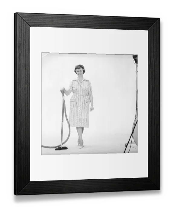 Framed Print : Cleaning day in the 1960s. A woman is standing holding a vacuum cleaner Framed Print : Cleaning day in the 1960s. A woman is standing holding a vacuum cleaner