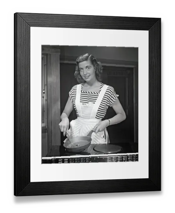 Framed Print : In the kitchen 1940s. A young woman smiles at the camera holding a frying pan and a whisk in her hands Framed Print : In the kitchen 1940s. A young woman smiles at the camera holding a frying pan and a whisk in her hands