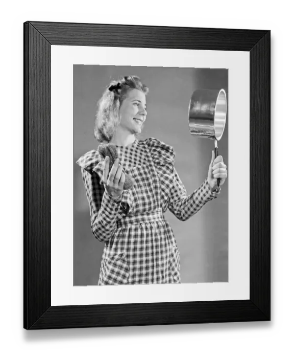 Framed Print : In the 1950s. A young woman looks happy with the cleaning result she made with the metal wool