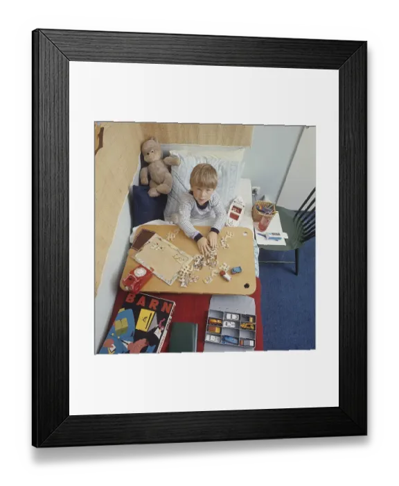 Framed Print : A boy in bed in the 1960s. He probably has a cold and needs to stay home