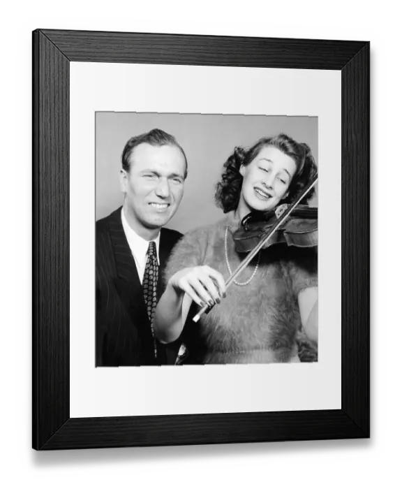 Framed Print : Noice in the 1940s. A young woman is playing the violin and judging by the man's facial expression, the violin is not in tune or she is really bad at playing it. He is seen making a gin of suffering. He is Rolf Botvid (1915-1998)