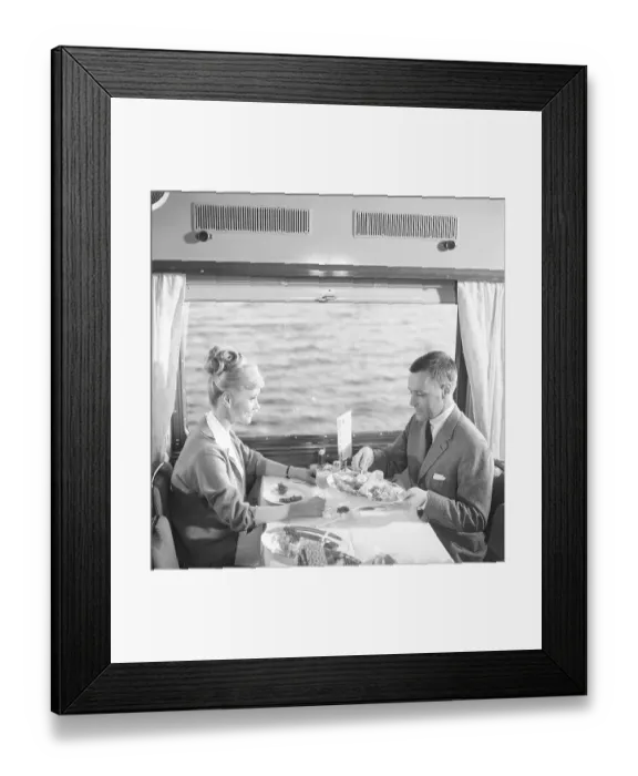Framed Print : Train travel in the 1960s. A couple in the restaurant car of the train is enjoying dinner together. She has a typical 1960s hairstyle. 1964 Kristoffersson ref DD107-8