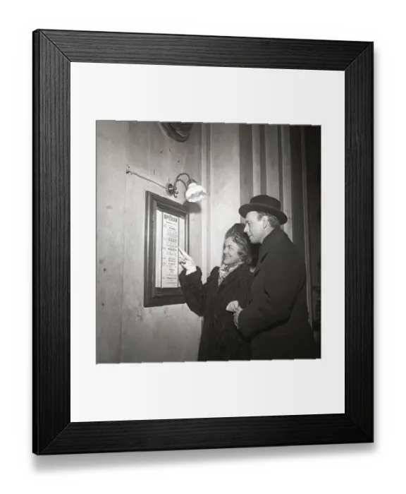 Framed Print : Couple in 1948. They stand at an information board Framed Print : Couple in 1948. They stand at an information board