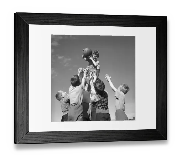 Framed Print : Rugby 1940. A young rugby player is holding the rugby ball in his hands while the other boys tries to reach it