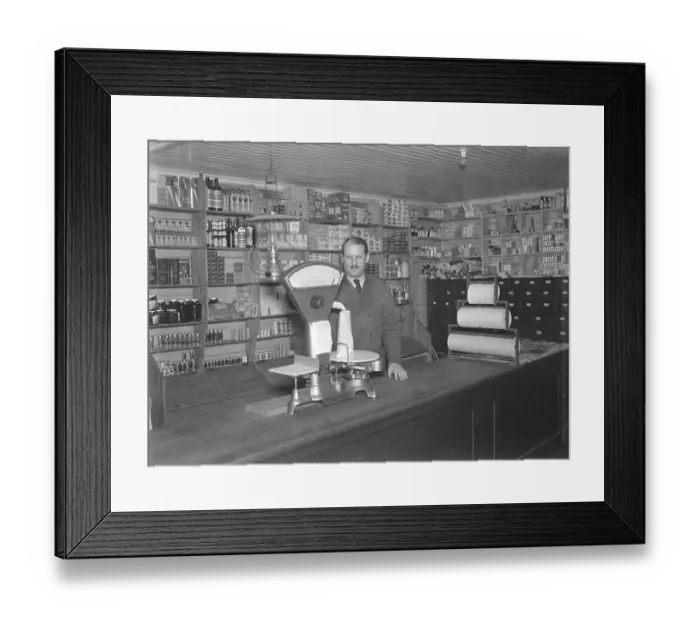 Framed Print : The merchant in the country store at Ornaes in the Stockholm archipelago weighs flour in a paper bag that is on a