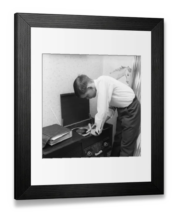 Framed Print : In the 1950s. A teenage boy has put on a gramophone record