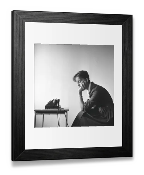 Framed Print : Woman in the 1950s. A young woman seen sitting by the telephone as if she is waiting for someone to call