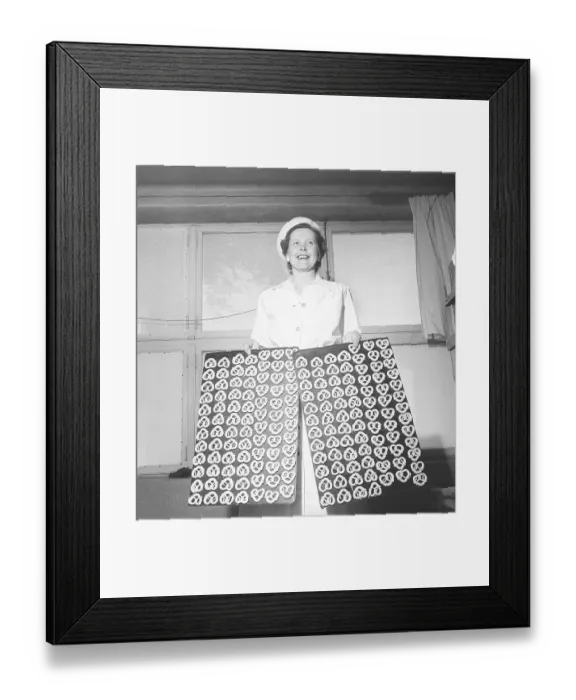 Framed Print : Happy woman in a bakery holding two trays of pretzels ready to bake