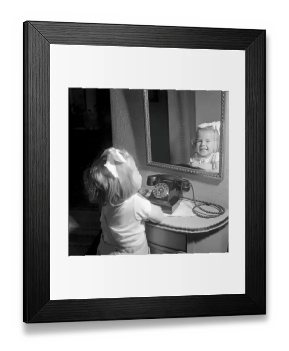 Framed Print : In the 1950s. A little girl pictured by a telephone
