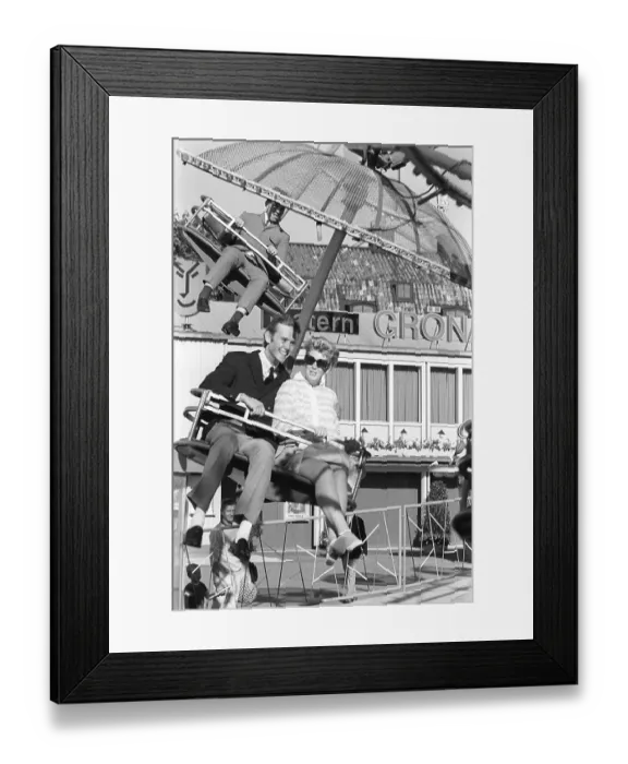 Framed Print : Amusement park in the 1960s. A couple is seen in one of the attractions that are offered on the grounds Framed Print : Amusement park in the 1960s. A couple is seen in one of the attractions that are offered on the grounds