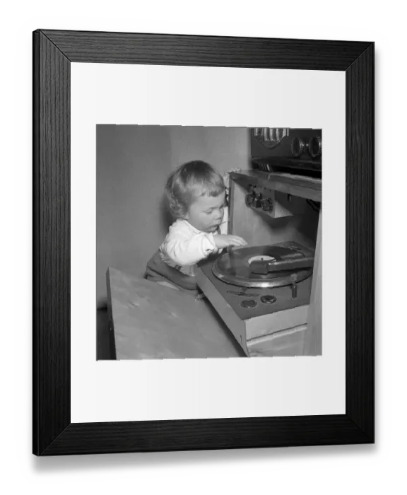 Framed Print : Child at a gramophone in the 1950s