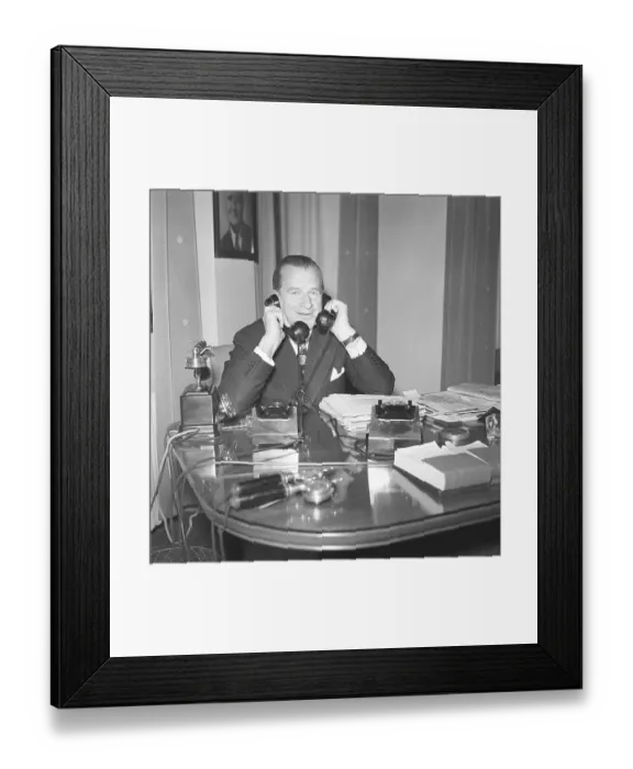 Framed Print : In the 1940s. A man in an office with two telephones looking busy