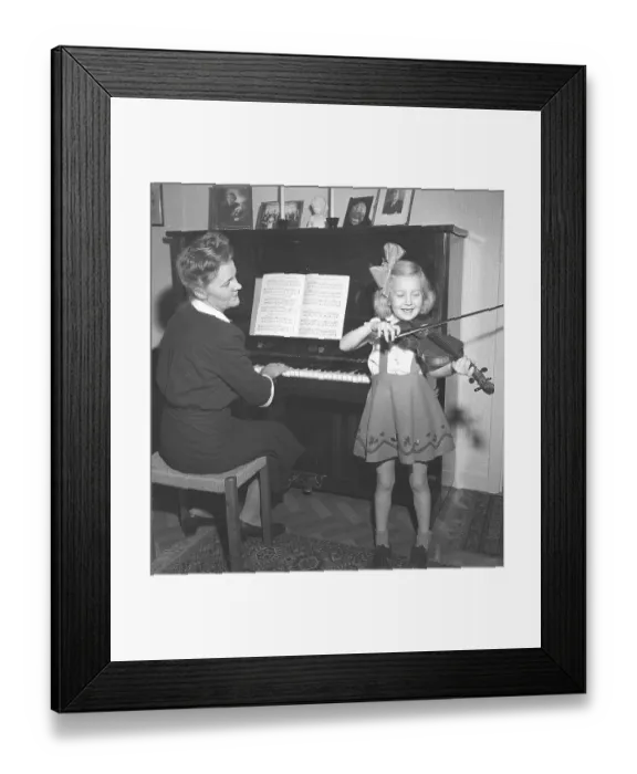 Framed Print : In the 1940s. A mother and her daughter play music together at home