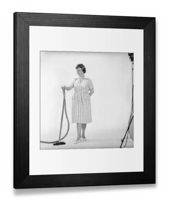 Framed Print : Cleaning day in the 1960s. A woman is standing holding a vacuum cleaner Framed Print : Cleaning day in the 1960s. A woman is standing holding a vacuum cleaner